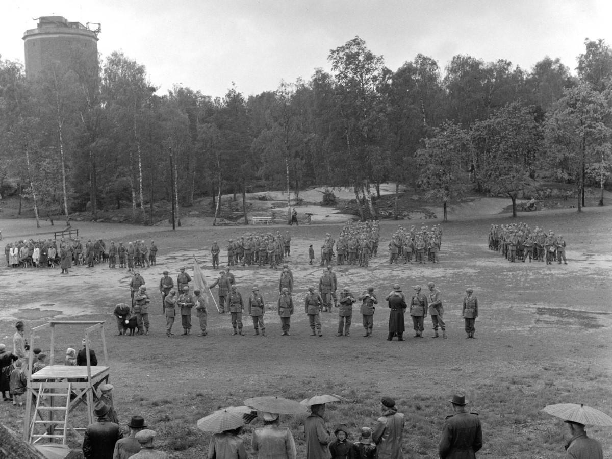 Svartvit bild med massor av människor samlade för att se soldaterna stå uppradade på Djäkneberget.