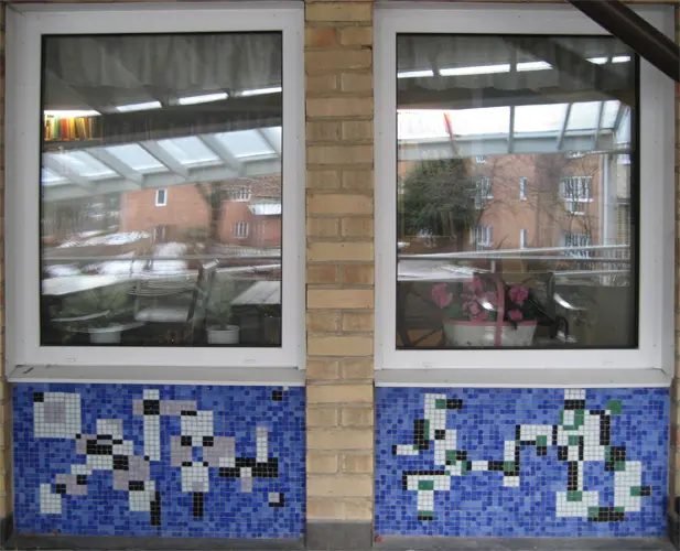Konstverket Mosaik på vägg under fönster.