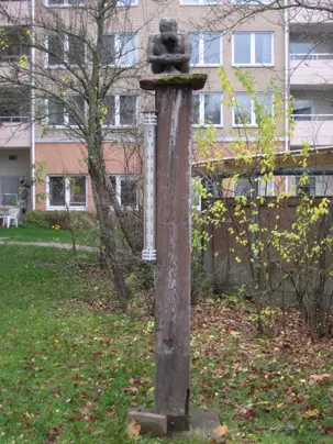Skulpturen Meditativ gestalt i trädgård.