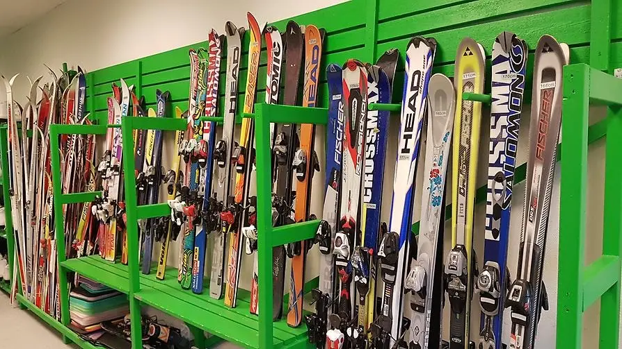 Ett fyrtiotal skidor som står lutade mot en vägg inne på Fritidsbanken.