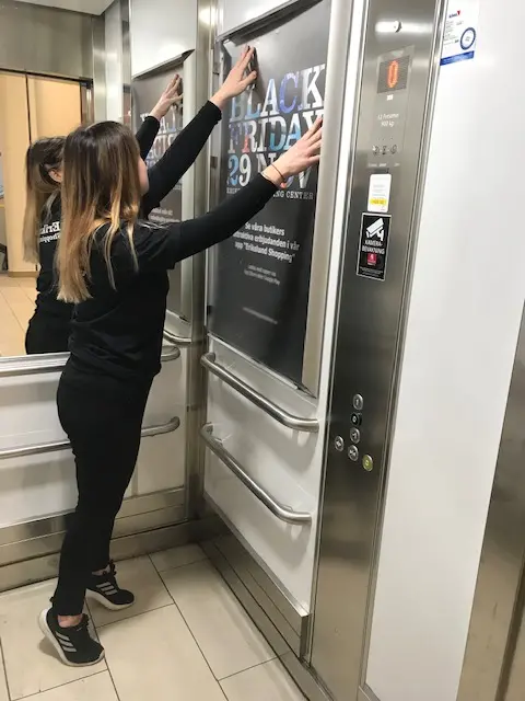 Person sätter upp en affisch i en hiss.