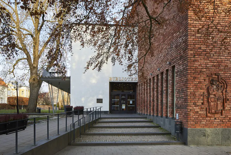 Trappan upp mot bibliotekets entréparti med tegelröd fasad på höger sida och konstverket Maria av Edvin Öhrström Foto: Lasse Fredriksson