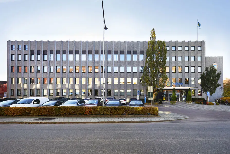 Vy rakt framifrån Västgötegatan mot entrésidan av polishuset med dess stabila betongfasad i fem våningsplan och långa rader med fönster. Foto: Lasse Fredriksson
