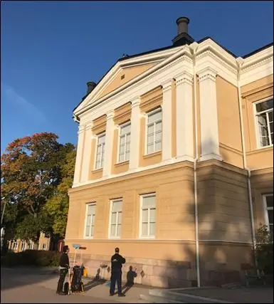 Två personer står utanför en byggnad på Rudbeckianska gymnasiet.