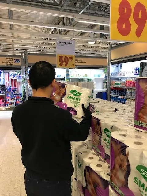 Person fyller på med förpackningar med toalettpapper i butiken. 