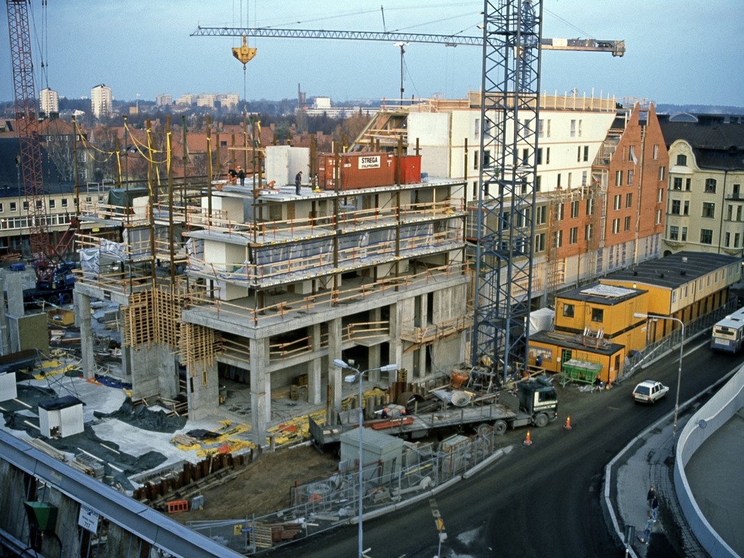 Byggarbetsplatsen där Skrapan byggs, lyftkranar och betongfundament.