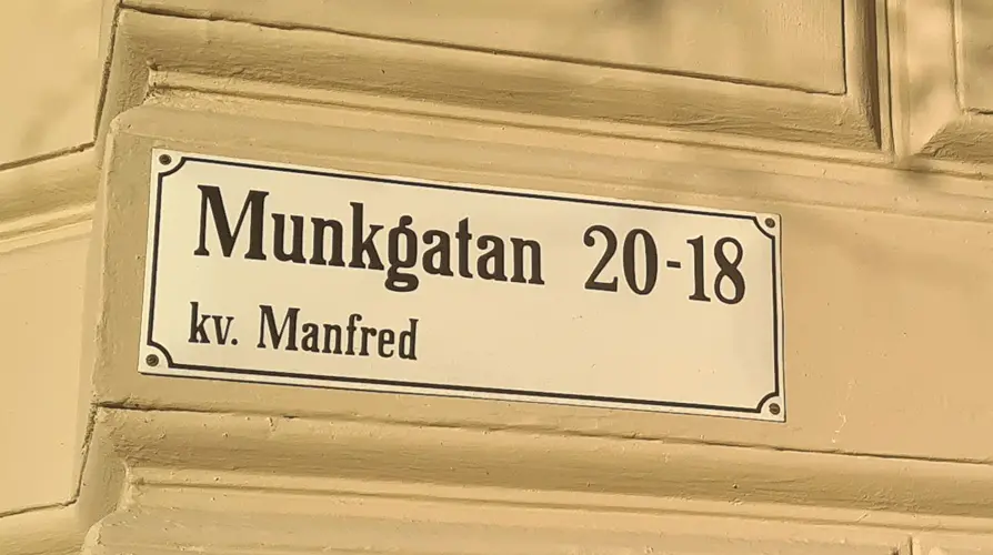 Skylt på fasad med gatan och kvarterets namn med texten Munkgatan 20-18 kv. Manfred