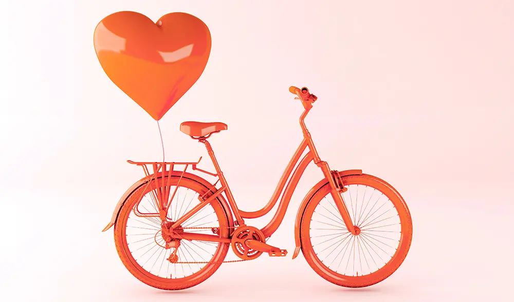 Bild på röd cykel med en hjärtformad ballong som svävar ovanför pakethållaren