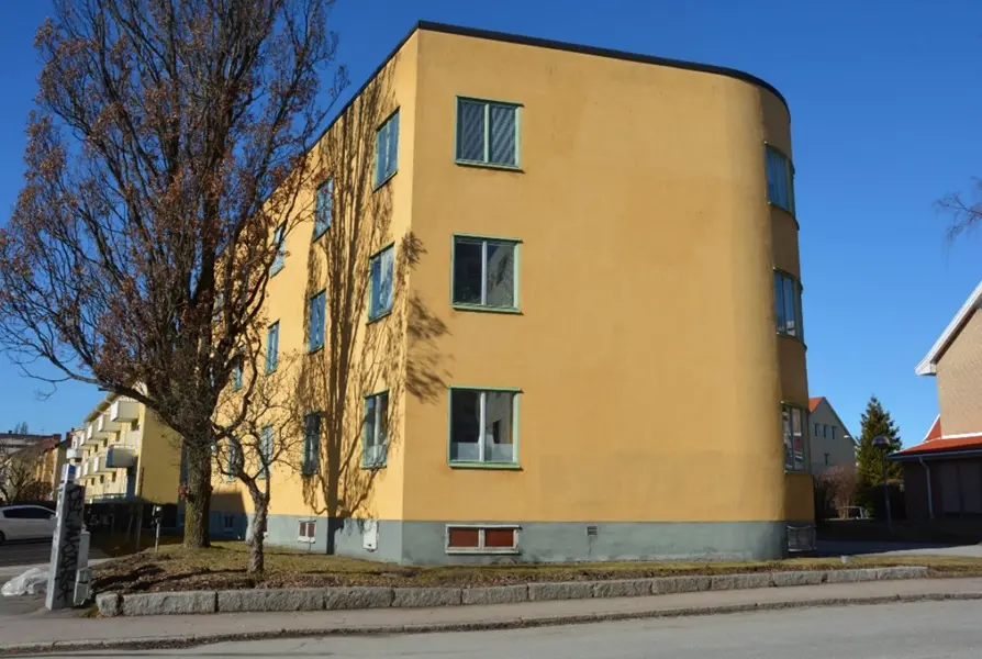 Gult flerbostadshus i tre våningar med raka linjer och platt tak i funktionalism på Kristiansborg. Fotograf Emma Karp Västmanlands läns museum.