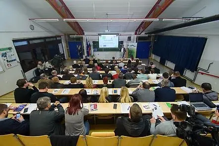 Översikt av en konferenslokal där ett fyrtiotal personer tittar på en presentation