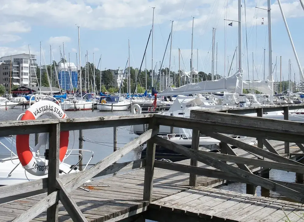 En brygga och livboj framför båtar i en hamn.