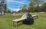 Ett konstverk med en bänk som går rakt igenom en stor sten. Copyright Alvaro Campo.