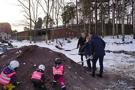 Politiker och barn gräver i grushög