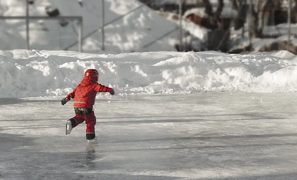 Barn som åker skridskor på en snöig isrink